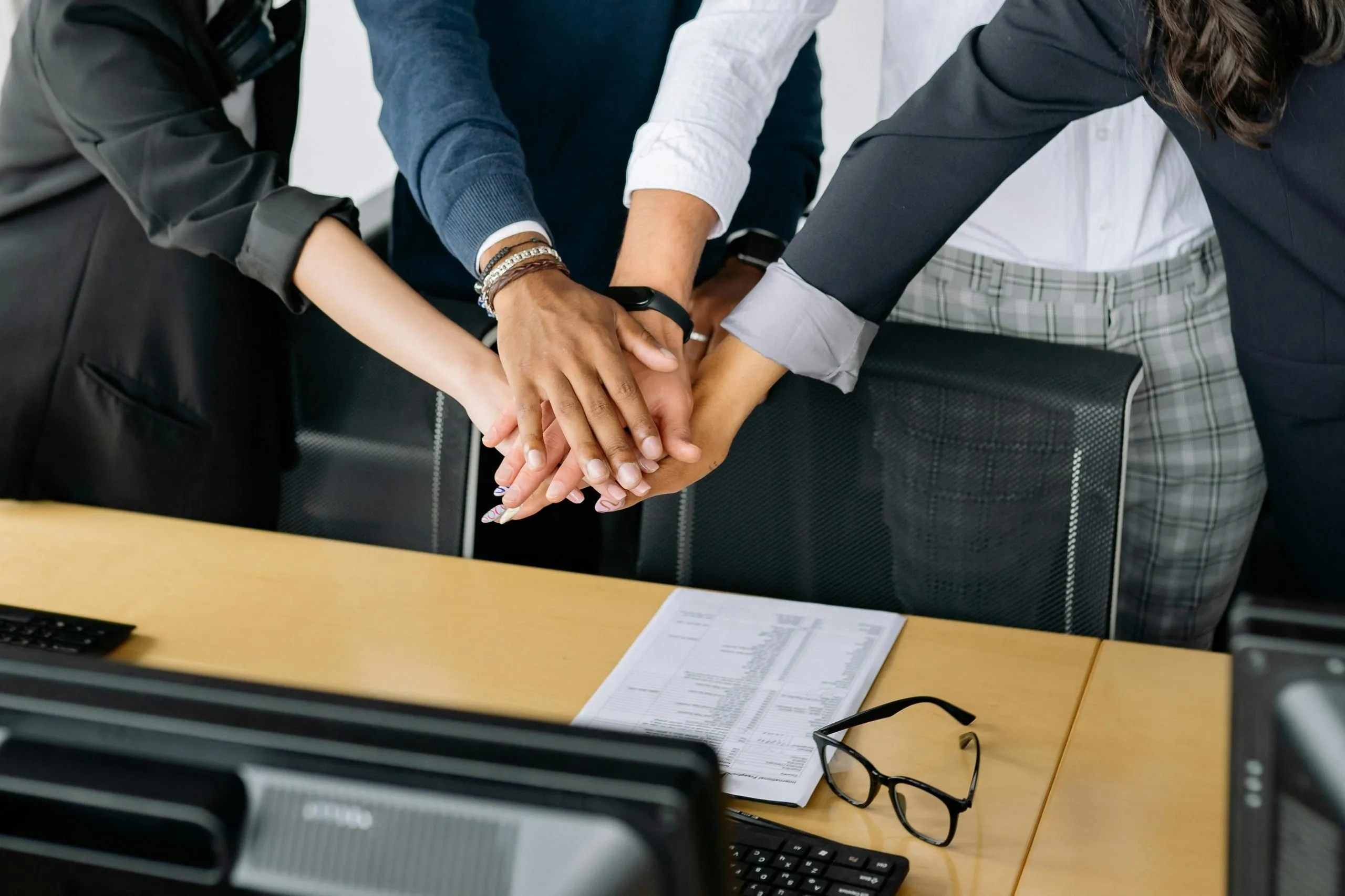 People in format attire with hands together in an office setting